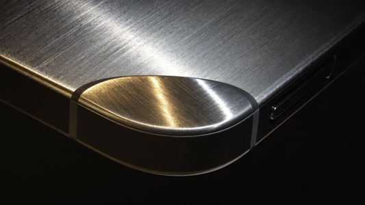 Hodinkee-style macro close-up of brushed-aluminum metal bumper texture and chamfered corner of a premium phone case — material study hero for the Galaxy Z Fold 7 metal phone case honest answer